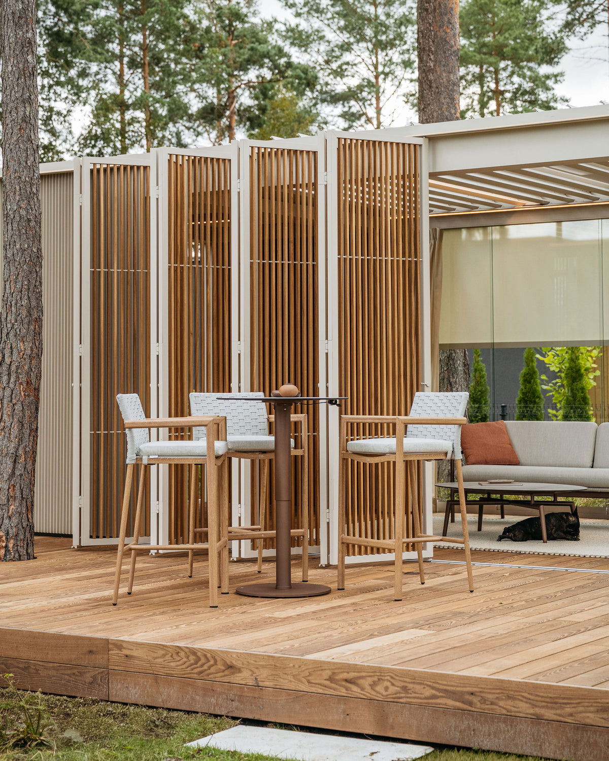 Table ENJOY Dark Bronze en position bar sur une terrasse sous pergola — table seule, tabourets et décoration non inclus